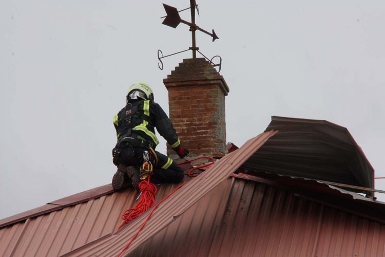 Los bomberos retiran las planchas metálicas de las cubiertas de El Castillo que han sido arrancadas por el temporal de viento