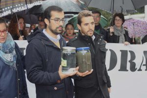 El alcalde de Arriate y el portavoz de IU muestran el agua antes y después de pasar por el pueblo.