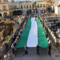 El PP de Málaga celebra el 4D desplegando una gran bandera andaluza en el Puente Nuevo